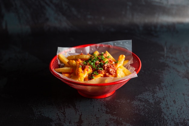 chicken nuggets in a red pot with french fries and cheese