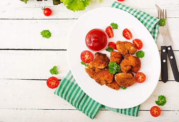 Chicken nuggets and sauce in plate on a white wooden background. Flat lay. Top view