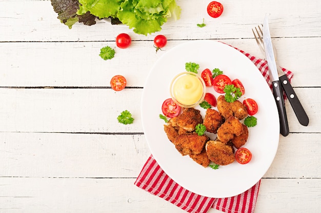 Chicken nuggets and sauce in plate on a white wooden table