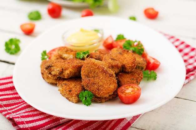 Chicken nuggets and sauce in plate on a white wooden table