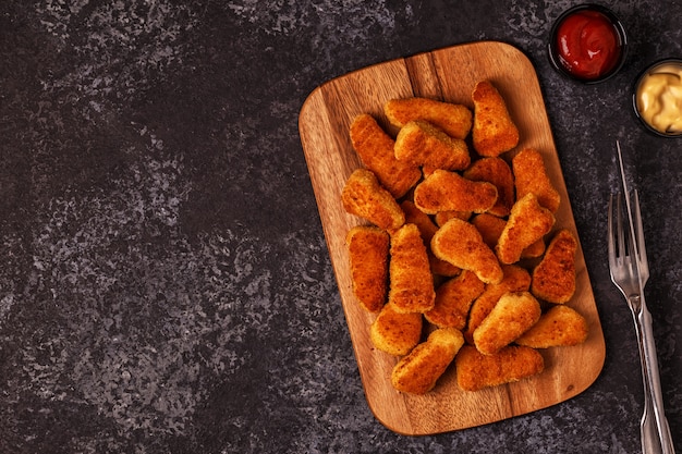 Chicken nuggets with sauces on dark surface