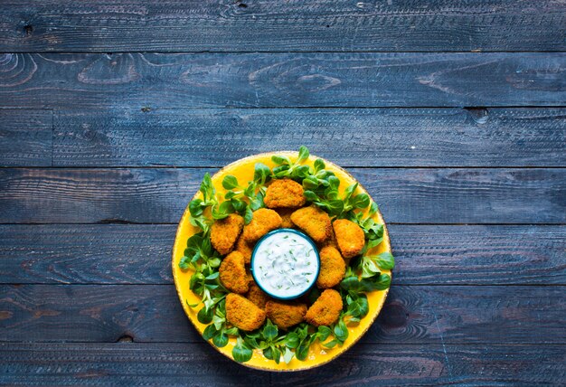 Chicken nuggets with yogurt sauce on wood 