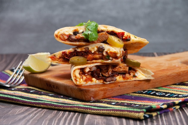 Chicken Quesadillas isolated on wooden board and mat side view of fastfood on wooden background