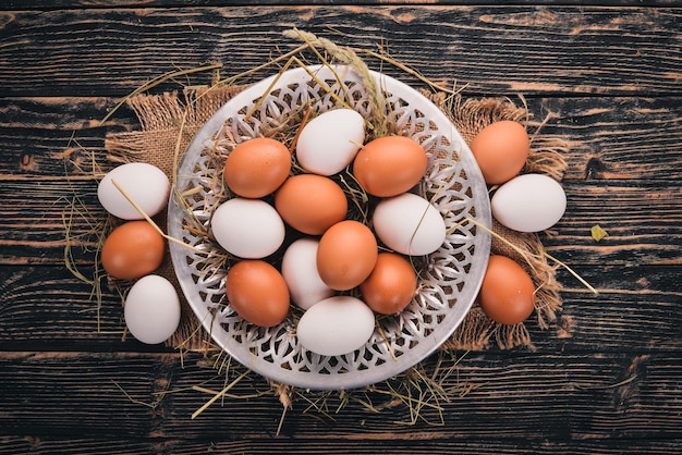 Chicken raw eggs on a metal plate On a wooden background Top view Copy space