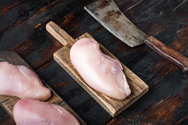 Куриное сырое филе с мясным ножом на темном деревянном фоне