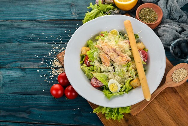 Chicken Salad and Fresh Vegetables Caesar Top view On a blue wooden background Copy space