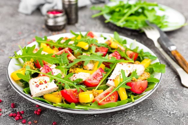 Photo chicken salad meat salad with fresh tomato sweet pepper arugula and grilled chicken breast chicken fillet with fresh vegetable salad