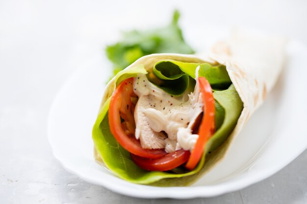 Chicken and salad tortilla wraps on white dish on ceramic