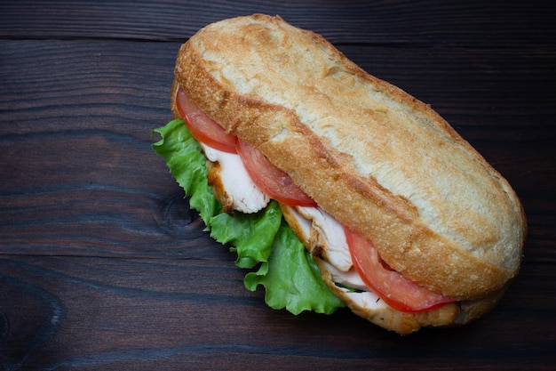 chicken sandwich on dark wood table