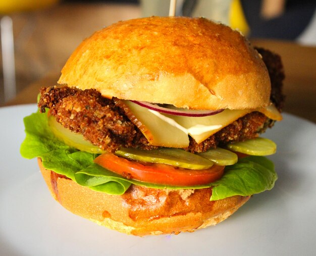 A chicken sandwich with cheese and tomato on a plate