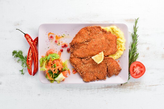 Chicken schnitzel with mashed potatoes on a plate On a wooden background Top view Free space for your text