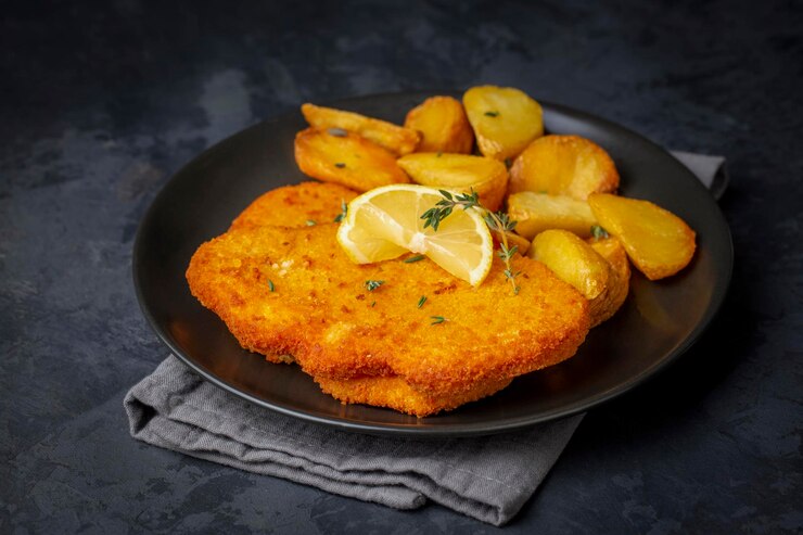 Photo chicken schnitzel with sauce, fried potatoes and lemon in a plate
