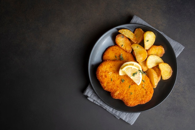 Photo chicken schnitzel with sauce fried potatoes and lemon in a plate