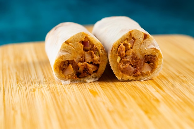 Chicken shawarma roll wrap isolated on wooden board side view of fastfood