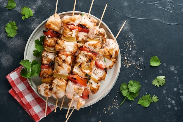 Kebab di shish di pollo o spiedini di kebab in un piatto di ceramica, spezie, erbe di coriandolo e verdure su sfondo bianco della tavola. barbecue materie prime per gulasch o shish kebab. vista dall'alto. spazio di copia gratuito