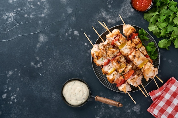 Shish kebab di pollo o spiedini di spiedini su tavola di legno, spezie, erbe aromatiche verdure