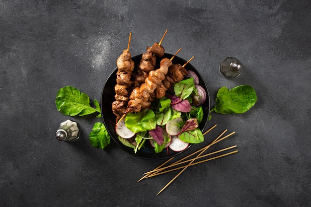 Chicken shish kebab with salad in plate top view