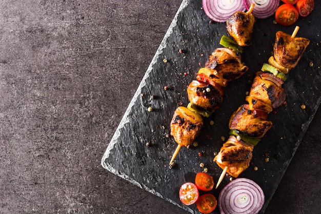 Chicken shish kebab with vegetables on black stone Top view Copyspace