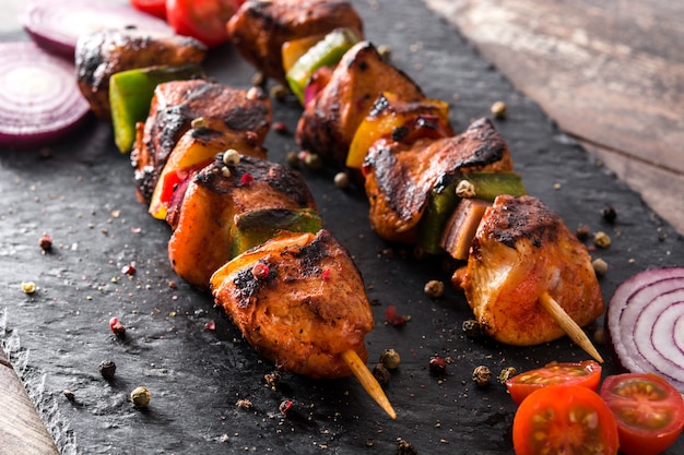 Chicken shish kebab with vegetables on black stone