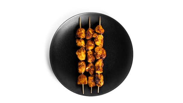 Chicken skewers on black plate isolated on white. Souvlaki isolated.