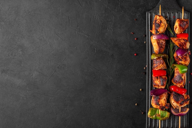Photo chicken skewers with slices of sweet peppers and onion shish kebab grilled meat on black background