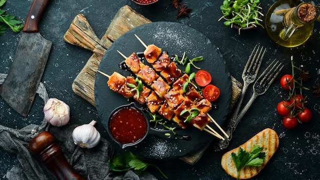 Chicken skewers with teriyaki sauce on a black stone plate Rustic style Barbecue menu