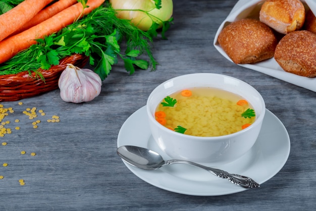 Chicken soup in bowl of broth and fresh vegetables