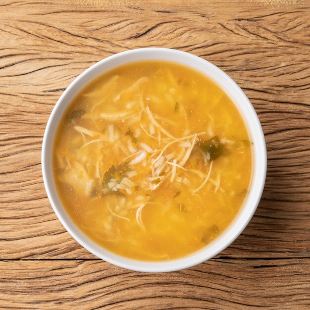 Chicken soup in a bowl over wooden table