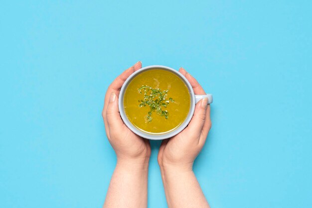 Chicken soup in a mug on a blue table above view