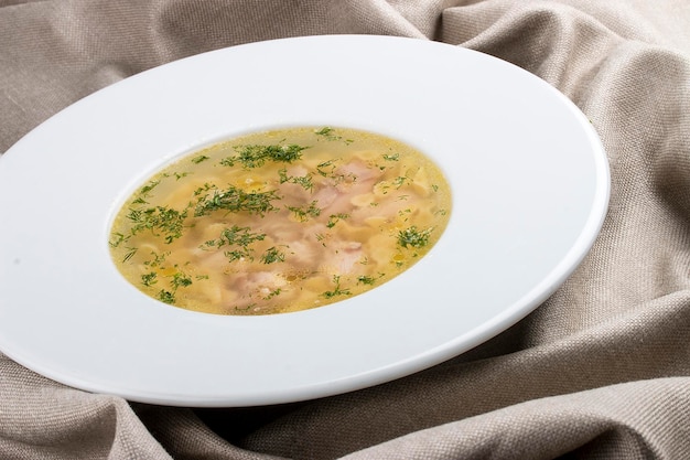 Фото Куриный суп на белой тарелке на текстильном фоне