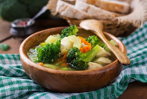 Chicken soup with broccoli green peas carrots and celery in bowl on a wooden background in rustic style
