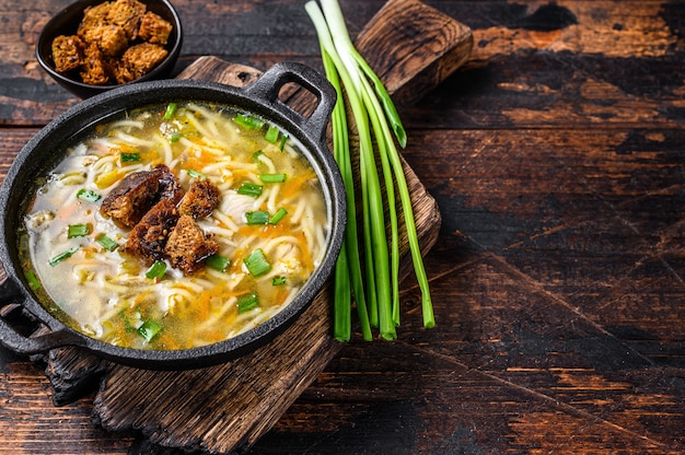 麺と野菜のチキンスープ。暗い木製のテーブル。上面図。