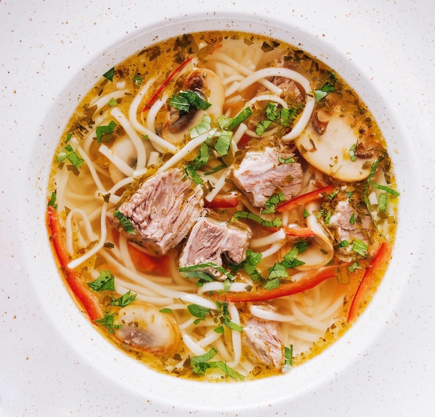 chicken soup with noodles and vegetables in white bowl