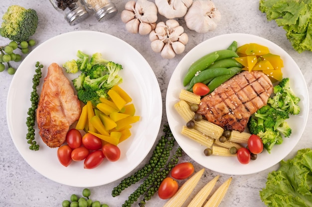 Photo chicken steak topped with white sesame peas tomatoes broccoli and pumpkin in a white plate