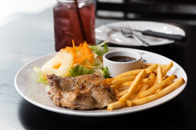 Photo chicken steak with french fries and sauce on table