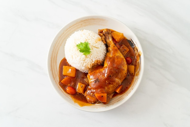 Chicken stew with tomatoes onions carrot and potatoes on plate with rice