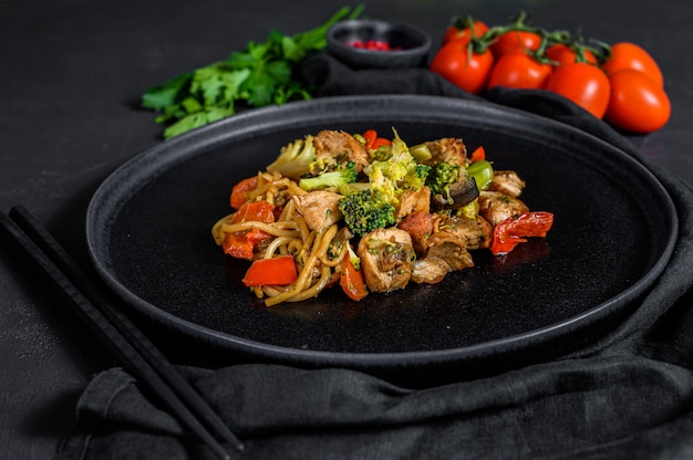 Chicken stir fry with vegetables soy sause, wok. Traditional asian food. stone black table