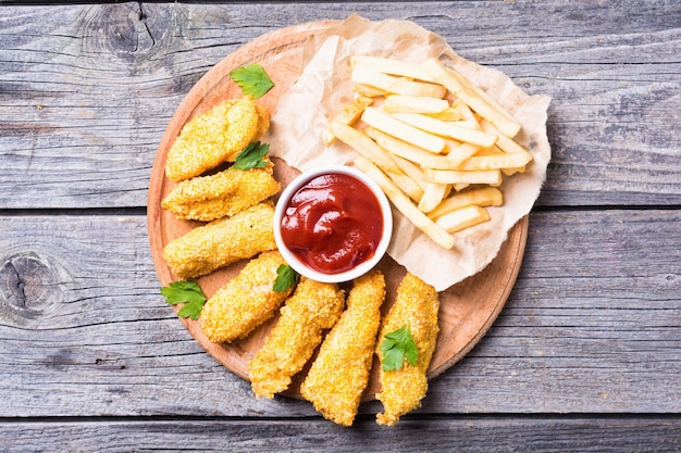 chicken strips and French fries on rustic wooden background