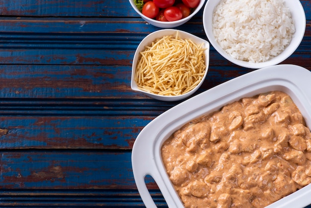 Chicken stroganoff accompanied with rice, salad and potato straw.