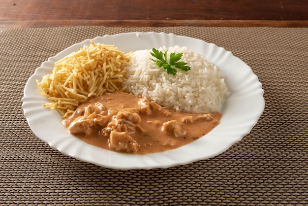 Chicken stroganoff accompanied with rice salad and potato straw