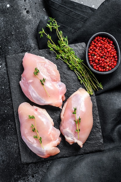 Chicken thigh fillet without skin. Black background. Top view.