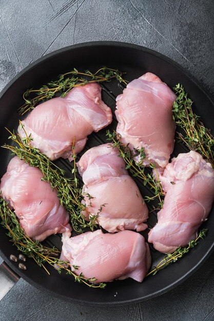 Cosce di pollo con timo su padella in ghisa su sfondo grigio vista dall'alto