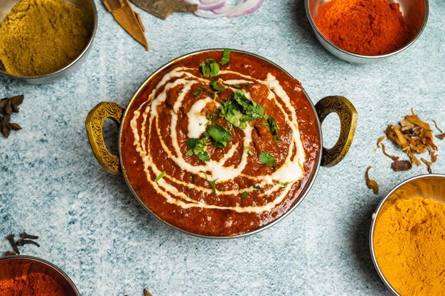 Цыпленок Tikka Butter Masala с соусом чили подается в блюде, изолированном на сером фоне, вид сверху на бангладешскую еду