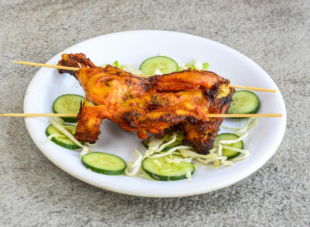 Chicken tikka leg piece served in plate isolated on grey background top view of pakistani and indian spices food