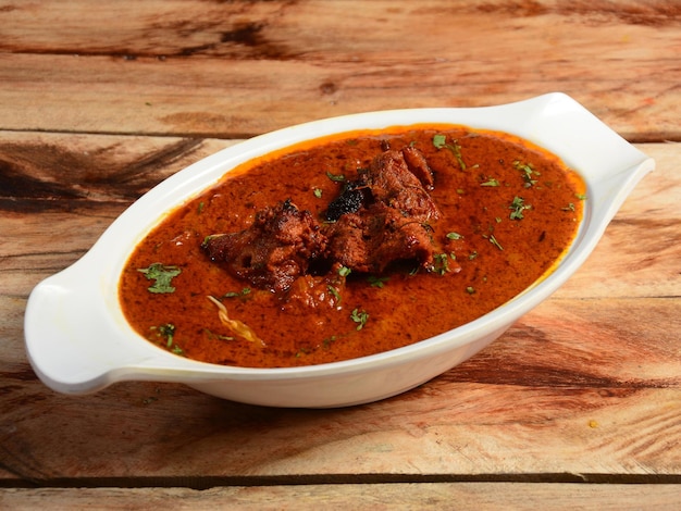 Chicken Tikka masala made of indian spices served in a bowl over a wooden rustic background selective focus