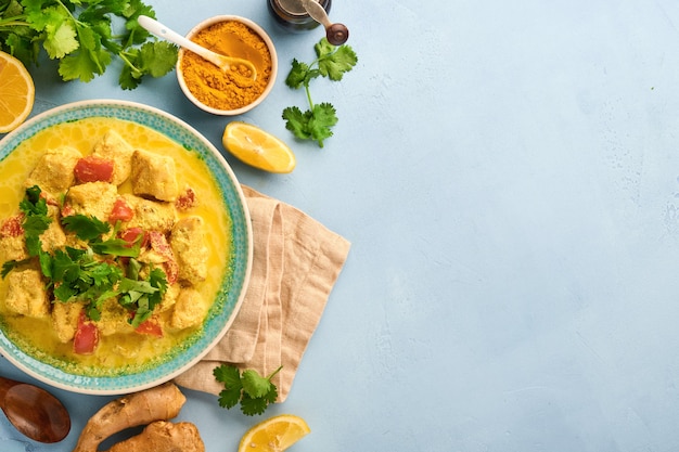 Chicken tikka masala. Traditional of indian cuisine curry and ingredients on dark background. Curry, lime, ginger, cilantro, chili, rice, herbs and spices. Top view with copy space.