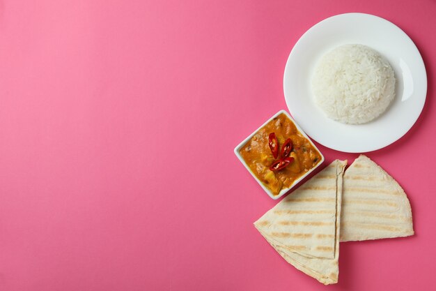 Chicken tikka with ingredients on pink background