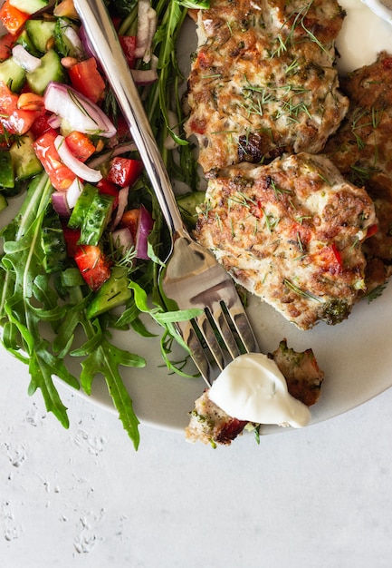 Chicken or turkey cutlets with vegetables and sauce on a plate. Delicious cutlets with salad.