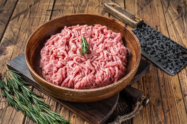 Photo chicken or turkey mince meat, raw poultry in a wooden plate. wooden table. top view.