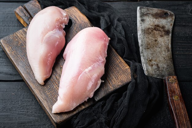 Chicken uncooked meat with butcher knife on black wooden table